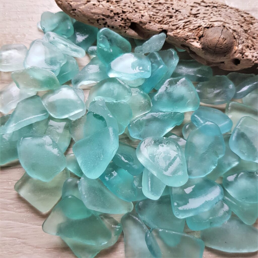 Small seafoam sea glass pieces displayed on a driftwood