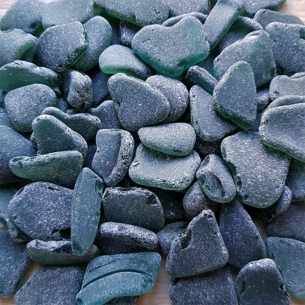 An artistic arrangement of frosty teal sea glass pieces on a smooth surface.