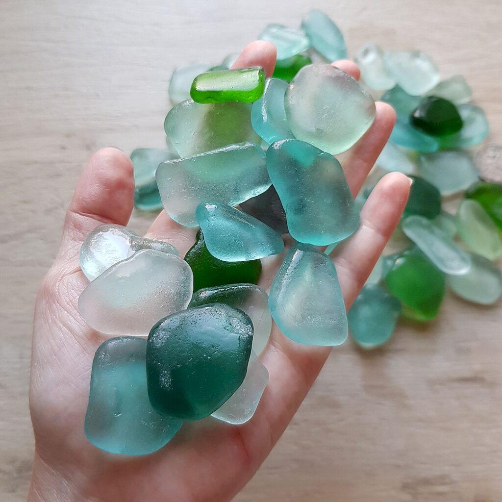 A handful of aqua-colored wet sea glass, sea foam and teal.