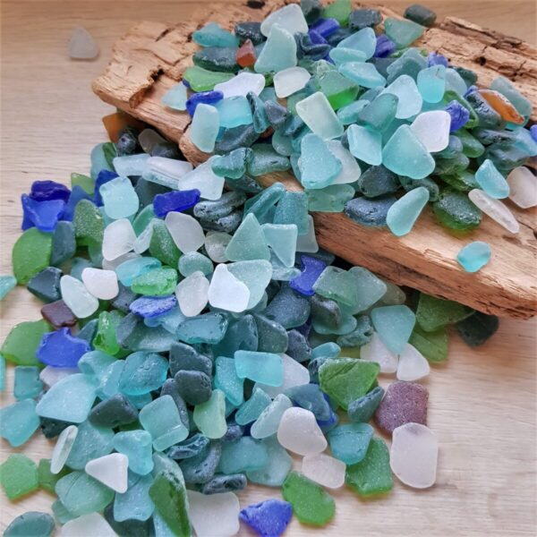 Artistic arrangement of colorful sea glass on a rustic wooden surface.