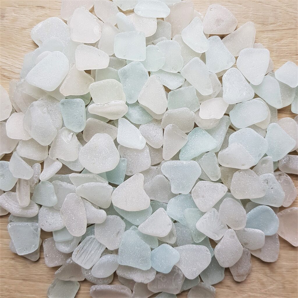 A collection of white sea glass pieces displayed on a smooth surface
