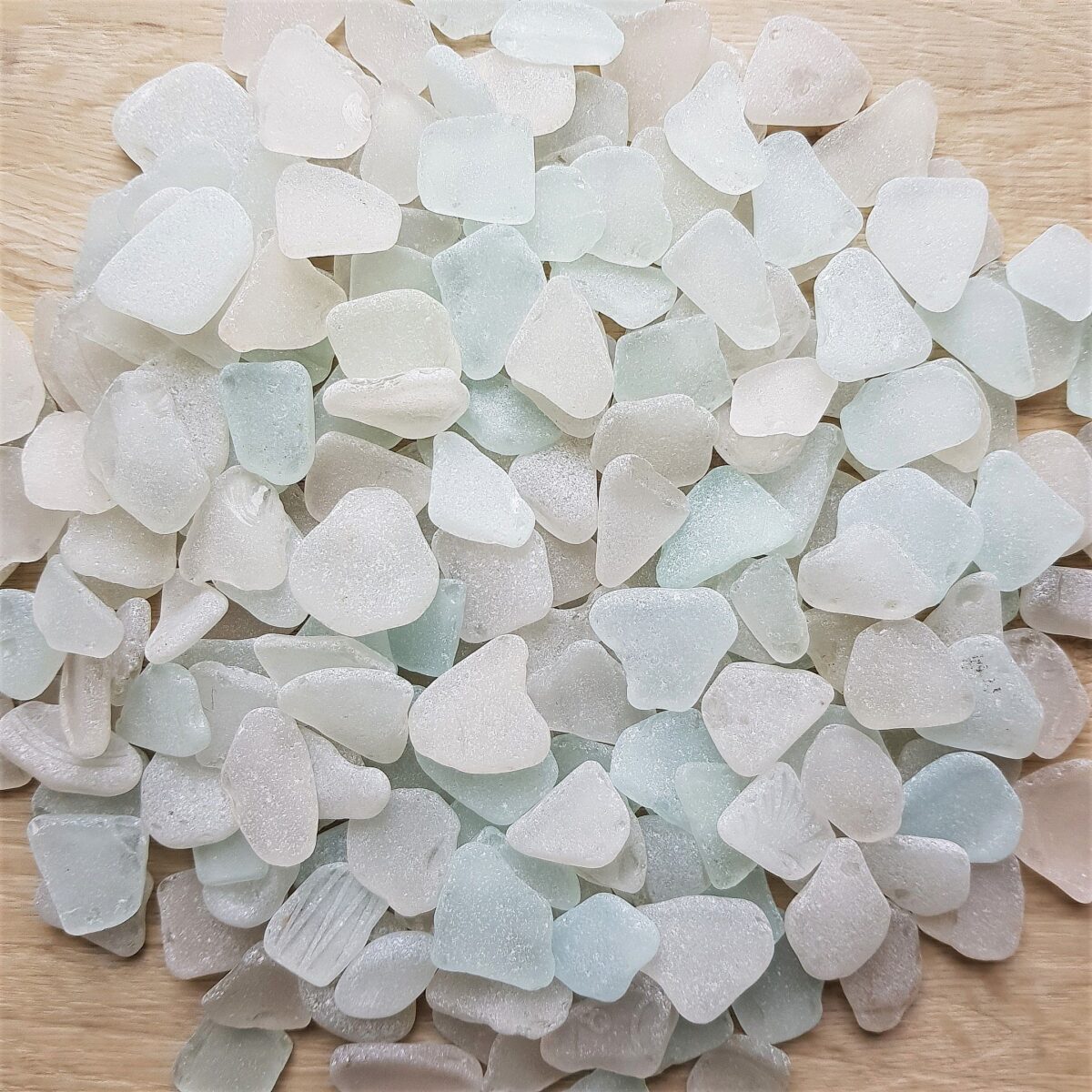 A collection of white sea glass pieces displayed on a smooth surface