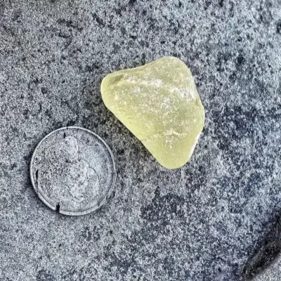 Crackled yellow sea glass displayed oa a stone
