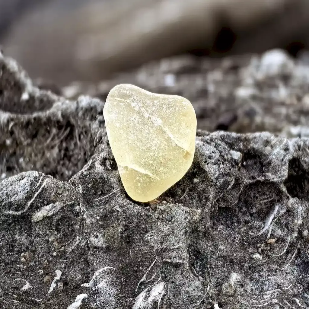 Crackled yellow sea glass sitting on a stone
