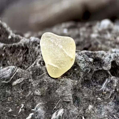 Crackled yellow sea glass sitting on a stone
