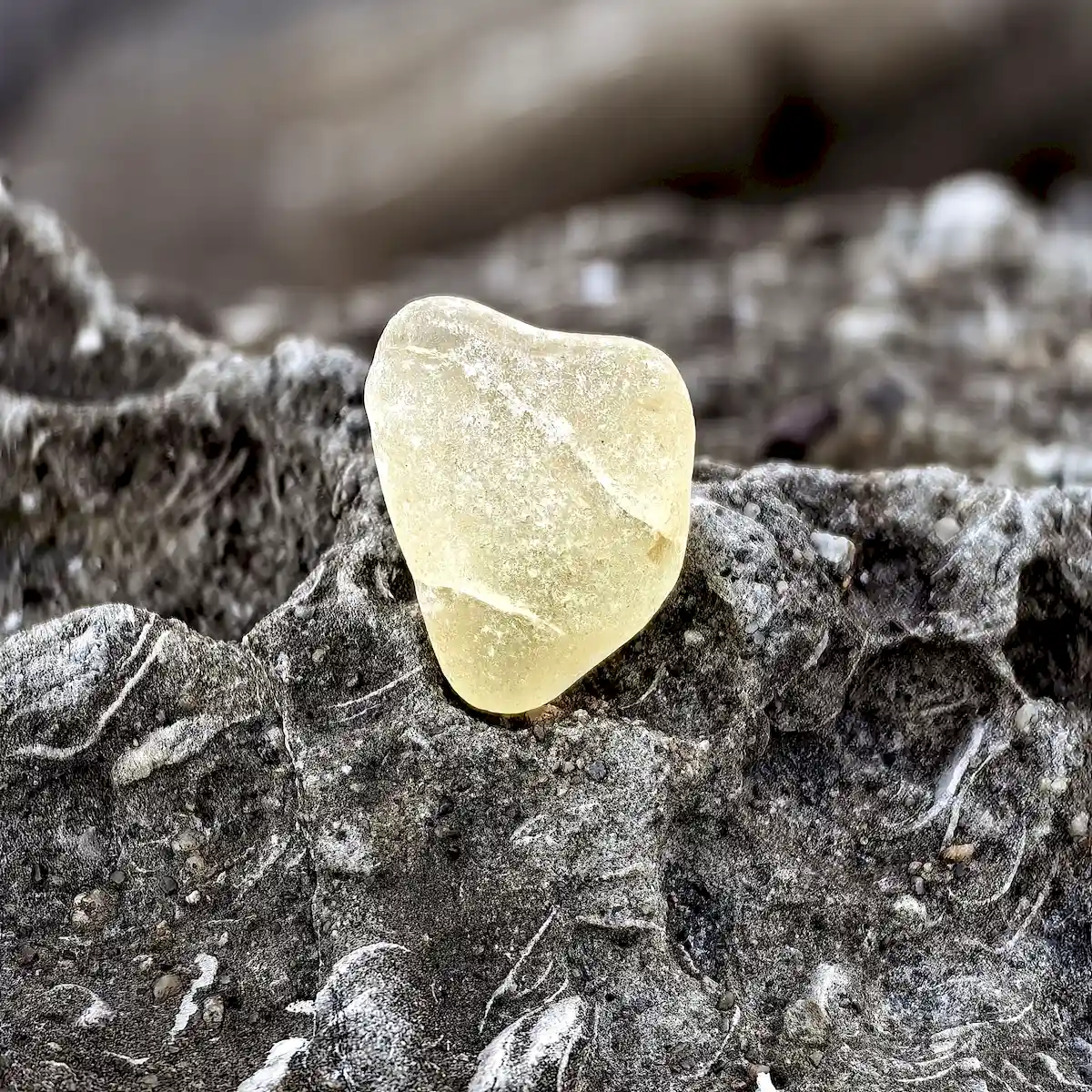 Crackled yellow sea glass sitting on a stone