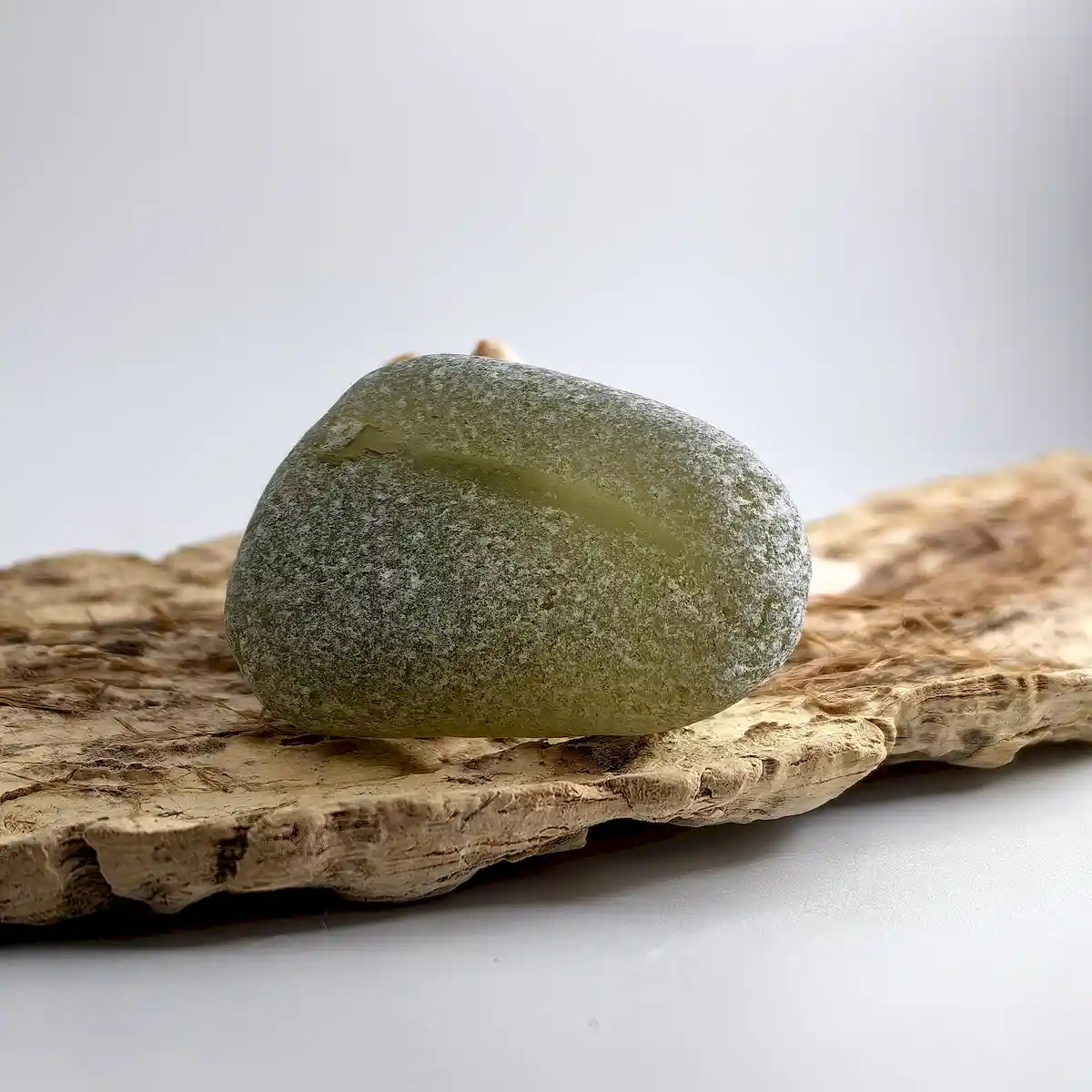 Extra Large Olive sea glass displayed on a driftwood