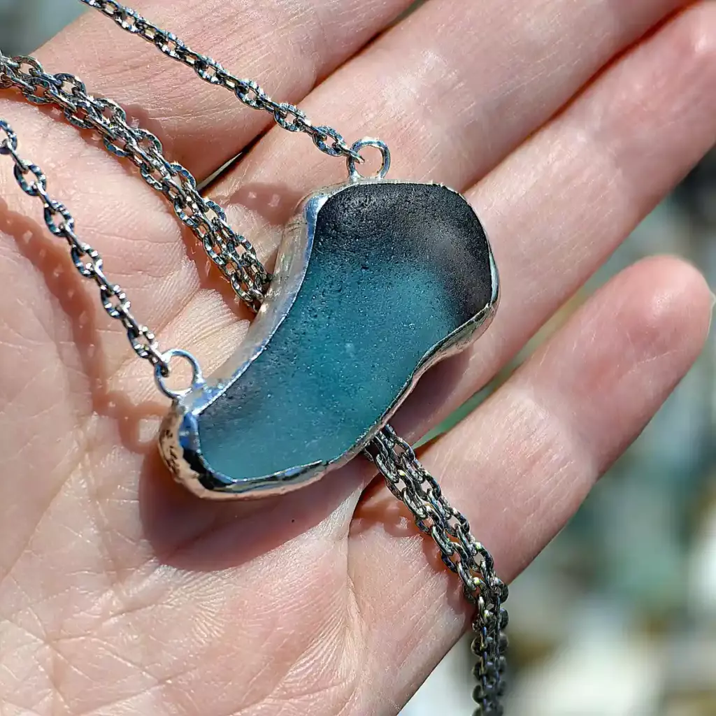 Teal Sea Glass Necklace displayed on a hand