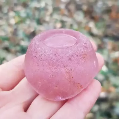 A powdery, cool-toned, watercolor pink sea glass (depression or rosaline glass)