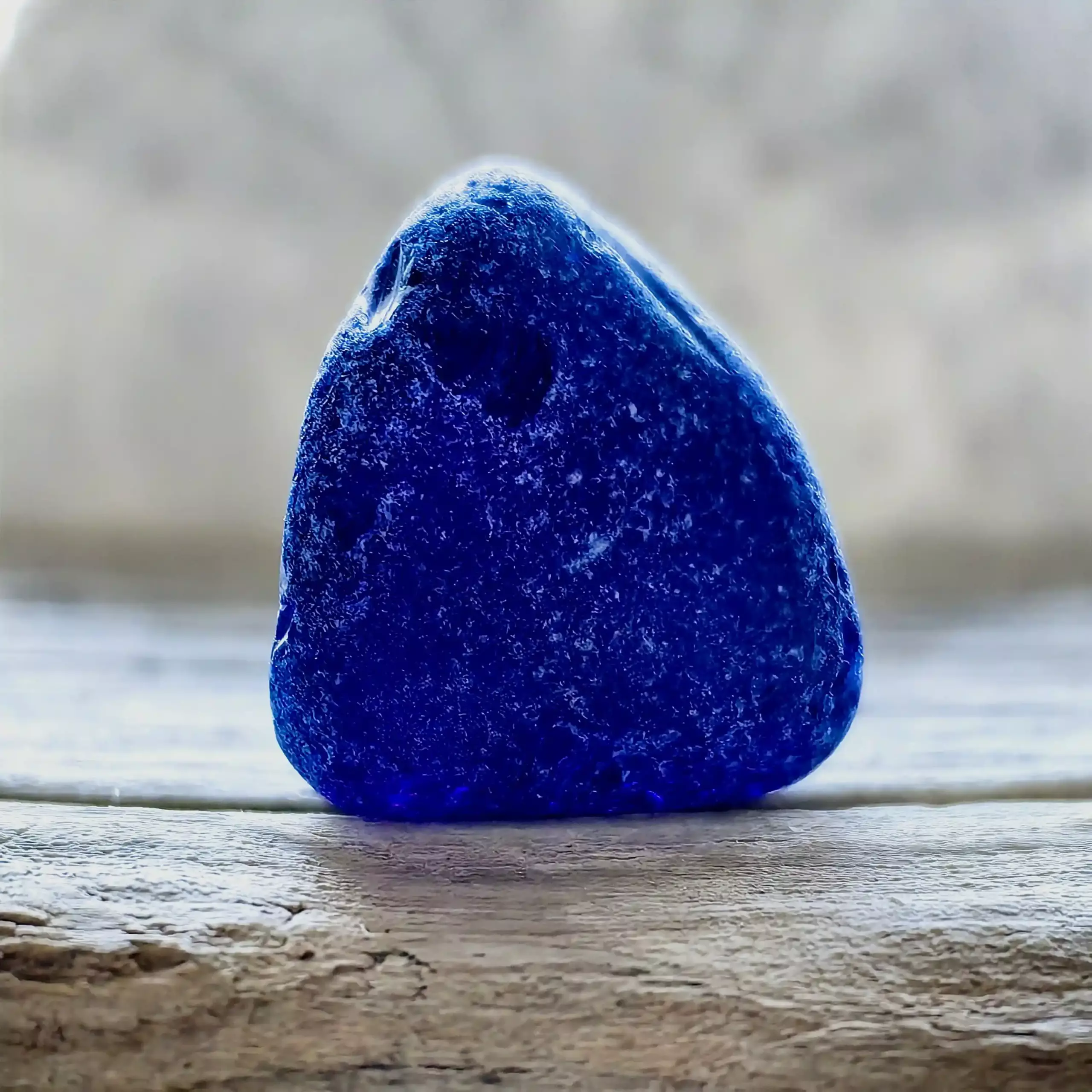 Genuine 1-inch multi-layered cobalt blue sea glass from Glass Beach showing hidden amber layer and natural C-marks under magnification.